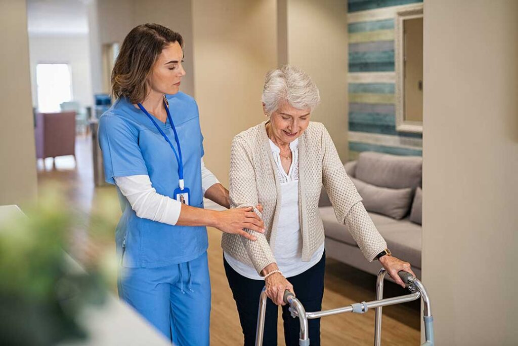 An elderly woman arranging family photos on a shelf in her new room, with a loved one nearby assisting.